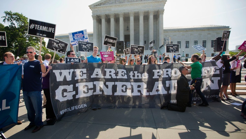 Demonstrators stand on the steps outside the Supreme Court in Washington, Monday, June 30, 2014.