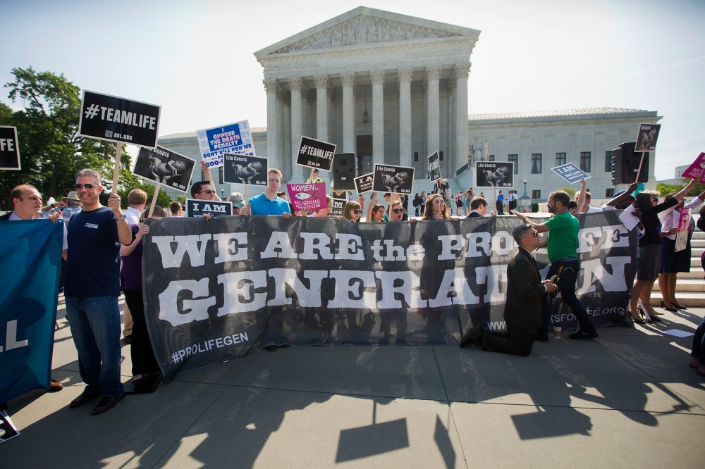 Demonstrators stand on the steps outside the Supreme Court in Washington, Monday, June 30, 2014.