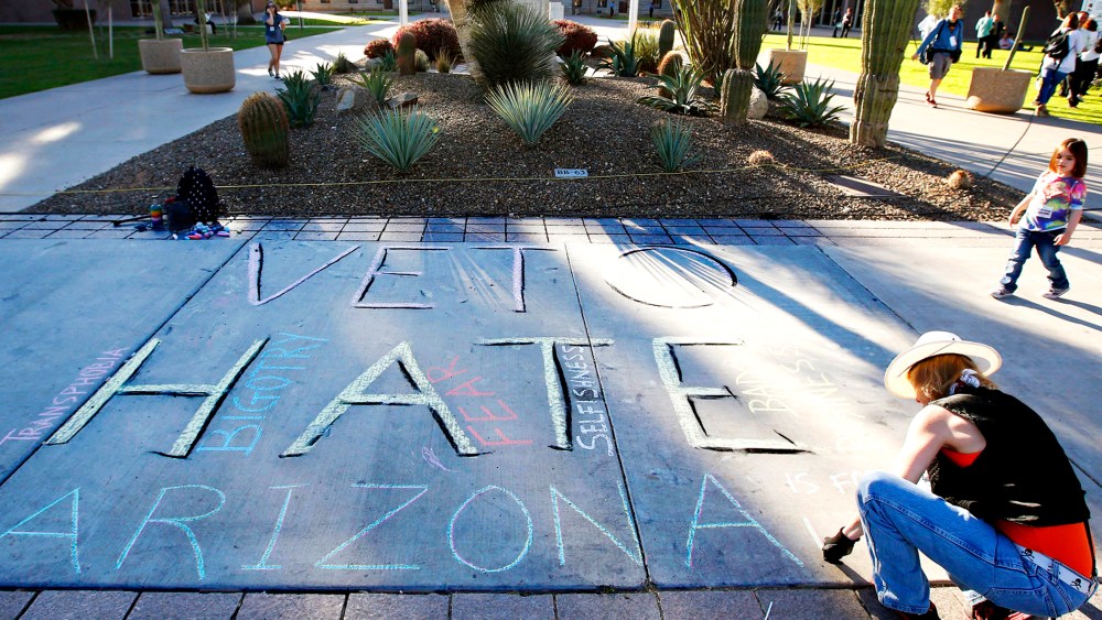 Margaret Jean Plews works on a chalk drawing as she joined nearly 250 gay rights supporters protesting SB1062 at the Arizona Capitol, Feb. 21, 2014.