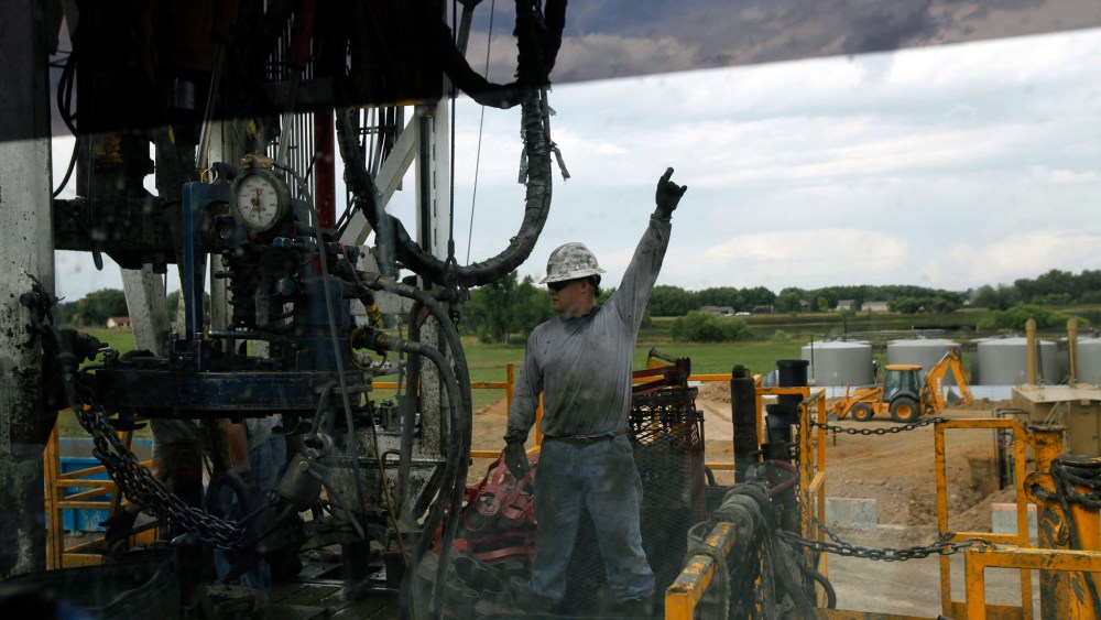 In an Aug. 25, 2009 file photo, a crew member with Anadarko Petroleum Corp., photographed through a car window, works on a drilling platform on a farm near Mead, Colo.
