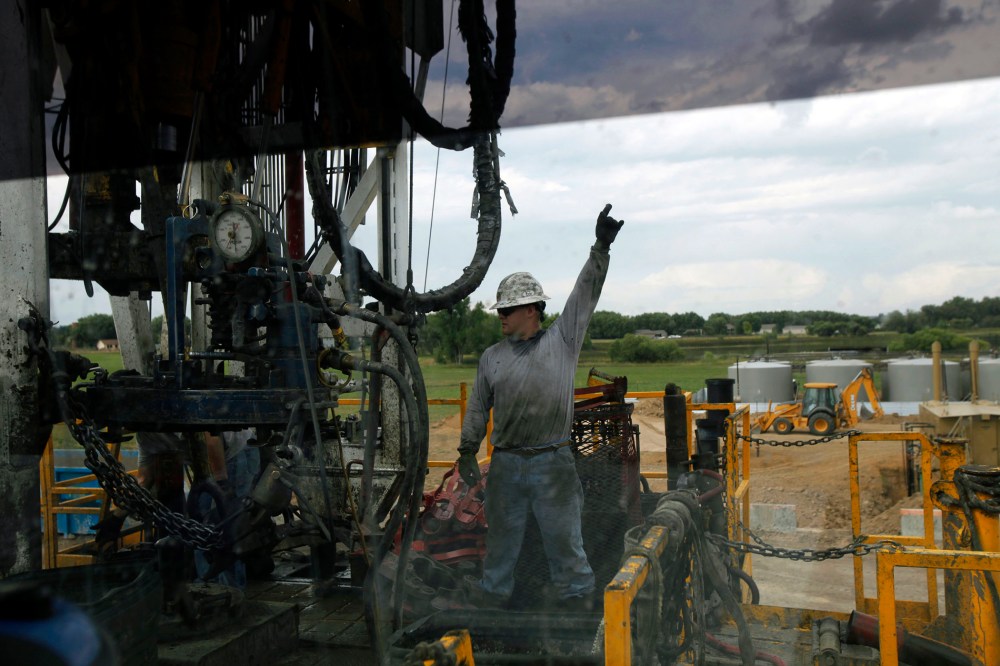 In an Aug. 25, 2009 file photo, a crew member with Anadarko Petroleum Corp., photographed through a car window, works on a drilling platform on a farm near Mead, Colo.