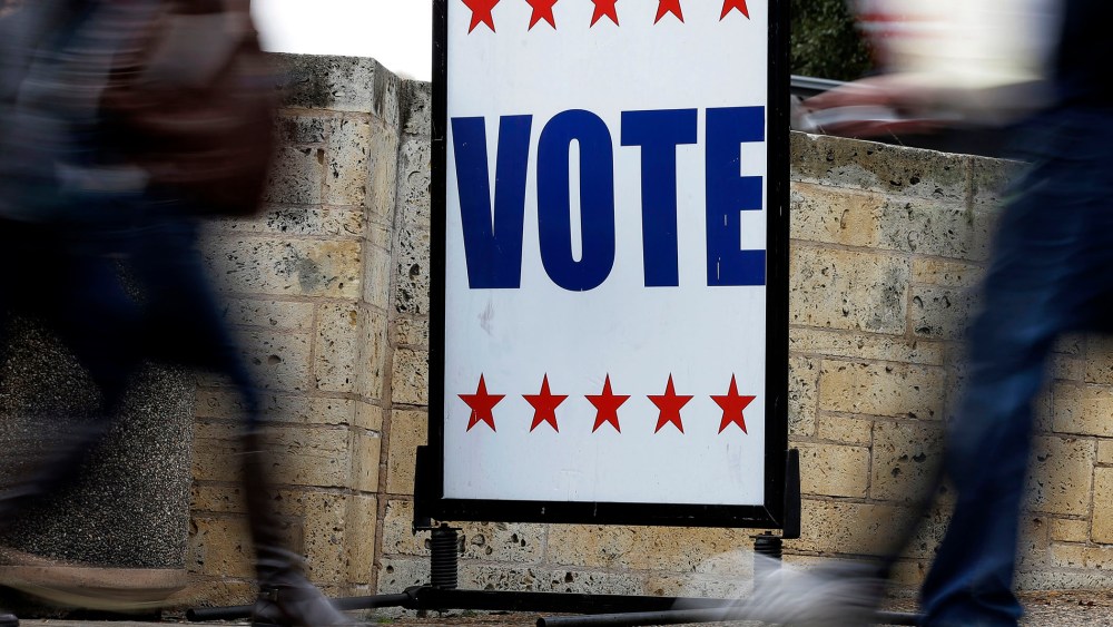 Pedestrians pass voting signs near an early voting polling site, in Austin, Texas.