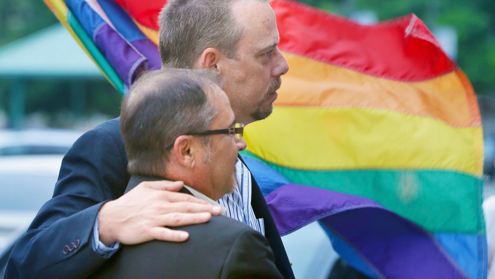 In this photo taken May 12, 2014, Shon DeArmon, top, and his partner James Porter carry a flag in support of the county issuing marriage licenses for same-sex couples at the Pulaski County Courthouse in Little Rock, Ark. (Photo by Danny Johnston/AP)