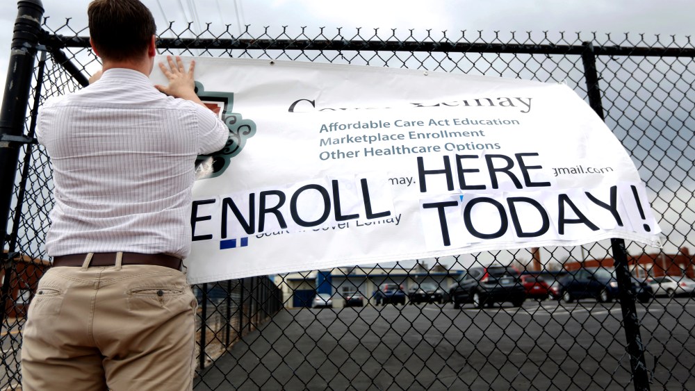 Ryan Witt hangs a sign outside offering assistance signing up for health insurance in St. Louis, March 31, 2014.