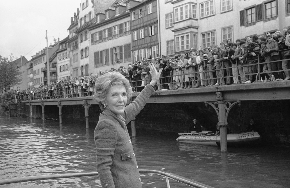 First Lady Nancy Reagan turns around and waves to a crowd alongside the river Ill where she was invited for a boat ride in this picturesque quarter, May 8, 1985, Strasbourg, France. (Anonymous/AP)