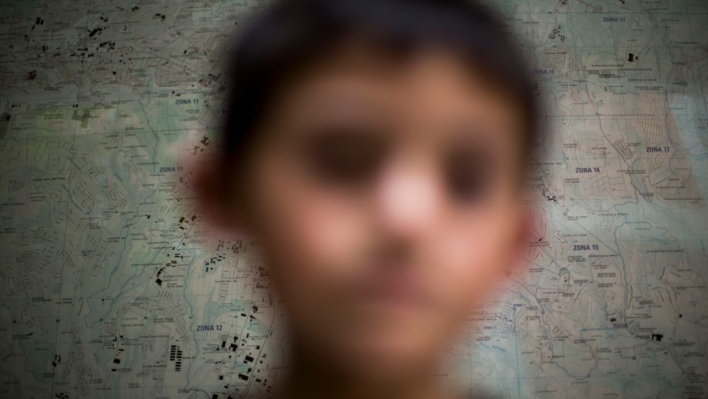 A Guatemalan child deported from the United State poses for photo in front of a map of the Guatemala City at an immigration shelter, June 19, 2014.