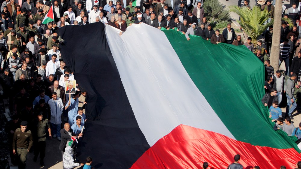 People hold a giant Palestinian flag during a rally in support of the Palestinian UN bid for observer state status, in the West Bank town of Jenin, Thursday, Nov. 29, 2012. The Palestinians are certain to win U.N. recognition as a state on Thursday but...