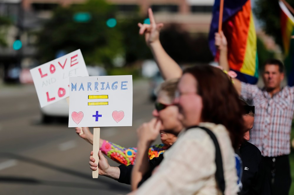 Gay marriage supporters hold up signs and rainbow flags for passing traffic at the Ada County Courthouse in Boise, Idaho, May 16, 2014.