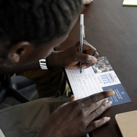 Dehjahn Swain, 19, signs a Commit To Vote card after registering to vote, Oct. 8, 2012 in Miami, Fla.