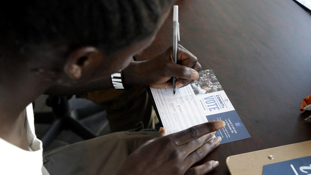 Dehjahn Swain, 19, signs a Commit To Vote card after registering to vote, Oct. 8, 2012 in Miami, Fla.