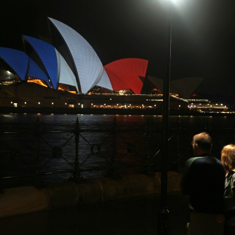 A couple look at the sails of the Sydney Opera House that are lit in the colors of the French flag in Sydney, Nov. 14, 2015, following the terrorist attacks in Paris. (Photo by Rick Rycroft/AP)