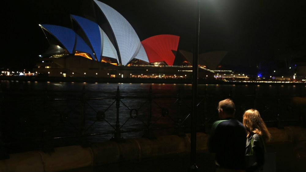 A couple look at the sails of the Sydney Opera House that are lit in the colors of the French flag in Sydney, Nov. 14, 2015, following the terrorist attacks in Paris. (Photo by Rick Rycroft/AP)