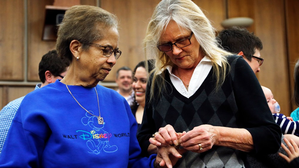 Pennye Mattson, right, places a wedding ring on Sherrie Tyler, left, while being married in a group by the Oakland County Clerk in Pontiac, Mich., March 22, 2014.