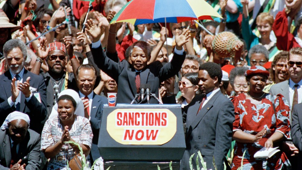 Nelson Mandela, deputy president of the African National Congress, gestures to a capacity crowd at the Oakland Coliseum on June 30, 1990, during the last stop of his eight city U.S. tour.