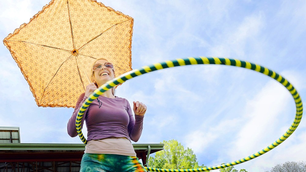 Amy Laura Hall hoola-hoops holding her parasol, during the  Durham's Earth Day Festival, in Durham Central Park, Durham N.C., Sunday, April 21, 2013. (AP Photo/The Herald-Sun, Bernard Thomas)