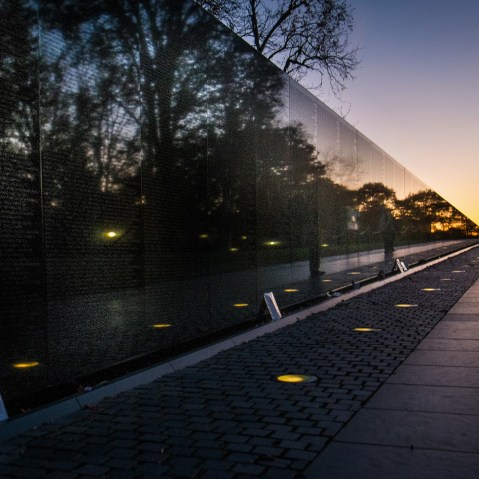 A visitor at the Vietnam War Memorial in Washington passes early in the morning on Veterans Day, Monday, Nov. 11, 2013, to look at the names inscribed on the wall.