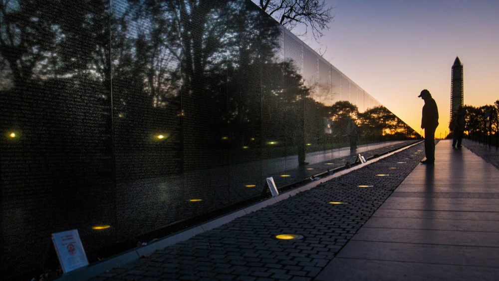 A visitor at the Vietnam War Memorial in Washington passes early in the morning on Veterans Day, Monday, Nov. 11, 2013, to look at the names inscribed on the wall.