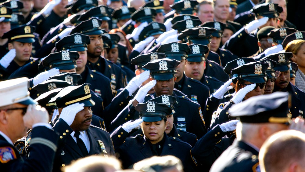 Thousands of police officers and others salute during the National Anthem as the funeral of New York City police officer Rafael Ramos begins at Christ Tabernacle Church in the Glendale section of Queens, where he was a member, Dec. 27, 2014, in New York.