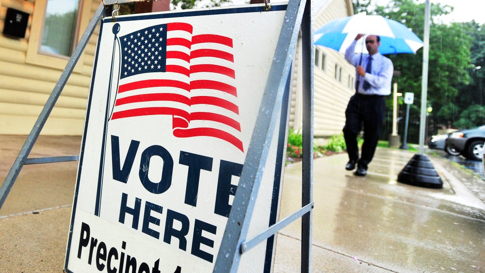 A man walks in the rain to vote at the Rochester Community House in Rochester, Mich. on Tuesday, Aug. 5, 2014.