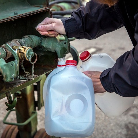 A local resident fills jugs with water at a distribution center in Charleston, W.Va., on Jan. 12, 2014.