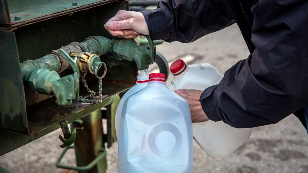 A local resident fills jugs with water at a distribution center in Charleston, W.Va., on Jan. 12, 2014.
