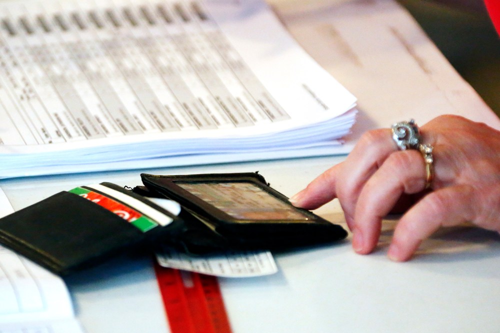 A Madison County election worker checks a voter's identification against a voting poll list before allowing him to vote in the party primary in Madison, Miss. on Tuesday, June 3, 2014.