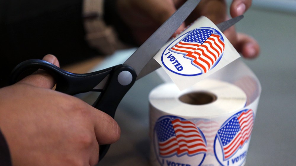 A volunteer hands out stickers to voters in Carson City, Nev., on Nov. 4, 2014. (Photo by Cathleen Allison/AP)