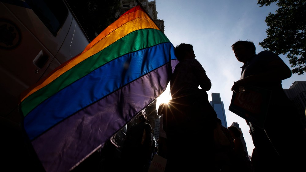 A person holds a gay pride flag during a rally. (Photo by Matt Slocum/AP)