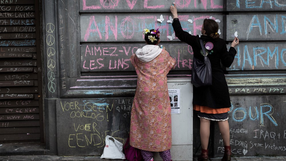 Two children write on a wall at a memorial for victims of attacks in Brussels on March 23, 2016. (Photo by Valentin Bianchi/AP)