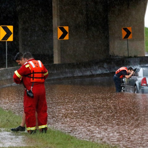 A firefighter looks into the window of a partially submerged car, checking to see if anyone is inside, May 23, 2015, in Oklahoma City. (Photo by Jim Beckel/The Oklahoman/AP)