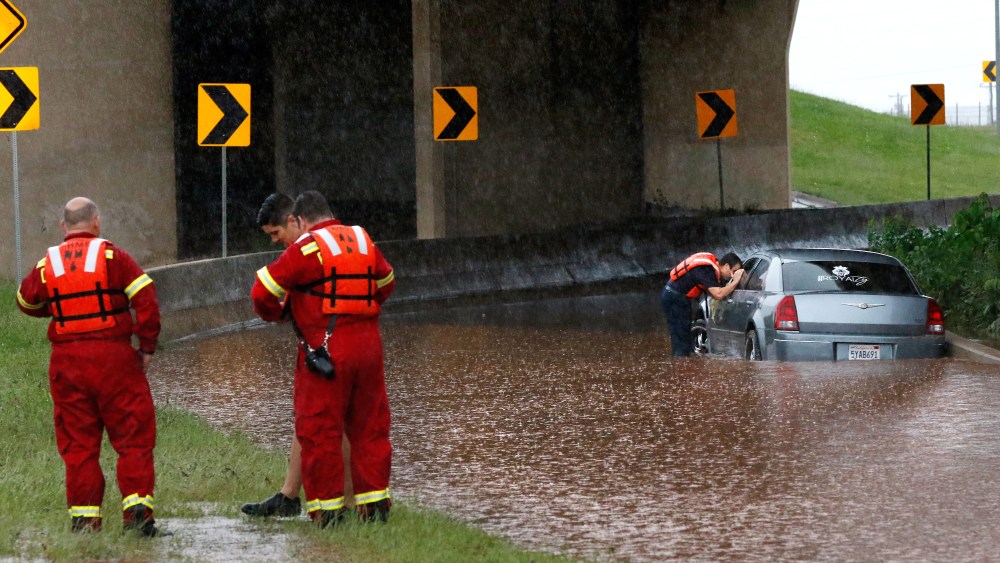 A firefighter looks into the window of a partially submerged car, checking to see if anyone is inside, May 23, 2015, in Oklahoma City. (Photo by Jim Beckel/The Oklahoman/AP)