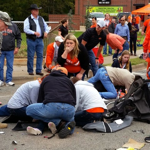 Bystanders help the injured after a vehicle crashed into a crowd of spectators during the Oklahoma State University homecoming parade, causing multiple injuries, Oct. 24, 2015 in Stillwater, Oka. (Photo by David Bitton/The News Press/AP)