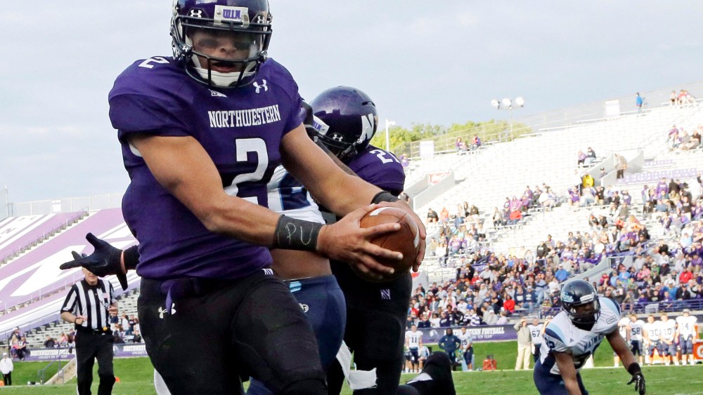 Northwestern quarterback Kain Colter (2), wears APU for "All Players United" on wrist tape as he scores a touchdown, Sept. 21, 2013.
