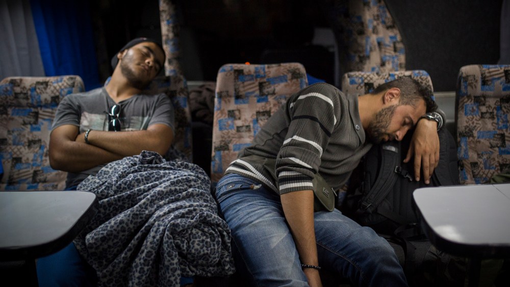 Mohammed al-Haj, right, and his friend Abdul-Rahman Babelly sleep on a bus traveling from Presevo, in southern Serbia, to the capital, Belgrade, their next stop en route to the Hungarian bordery, Sep. 12, 2015. (Photo by Santi Palacios/AP)