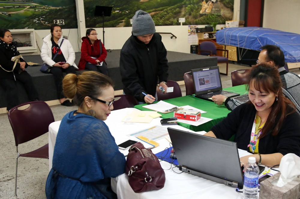 Mai Lo Lee, right, enrolls a woman in the state's insurance exchange, MNsure, as others (seated) from the Southeast Asian community wait their turn to register, on Feb. 13, 2015, in St. Paul, Minn. (Photo by Jim Mone/AP)