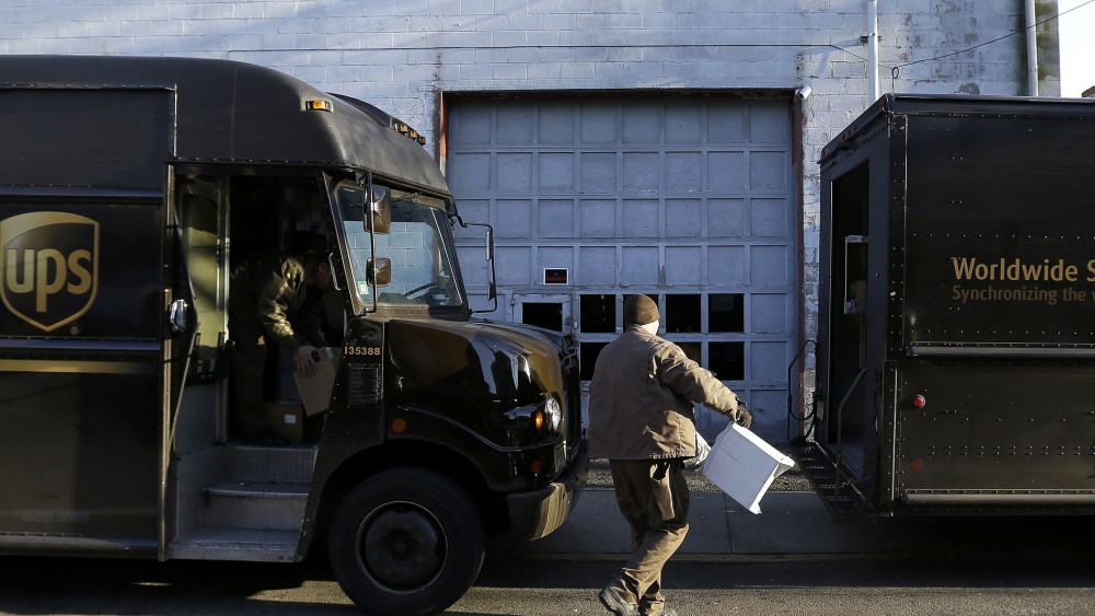 UPS delivery workers move packages from one truck to another, on Dec. 26, 2013, in Newark, N.J.