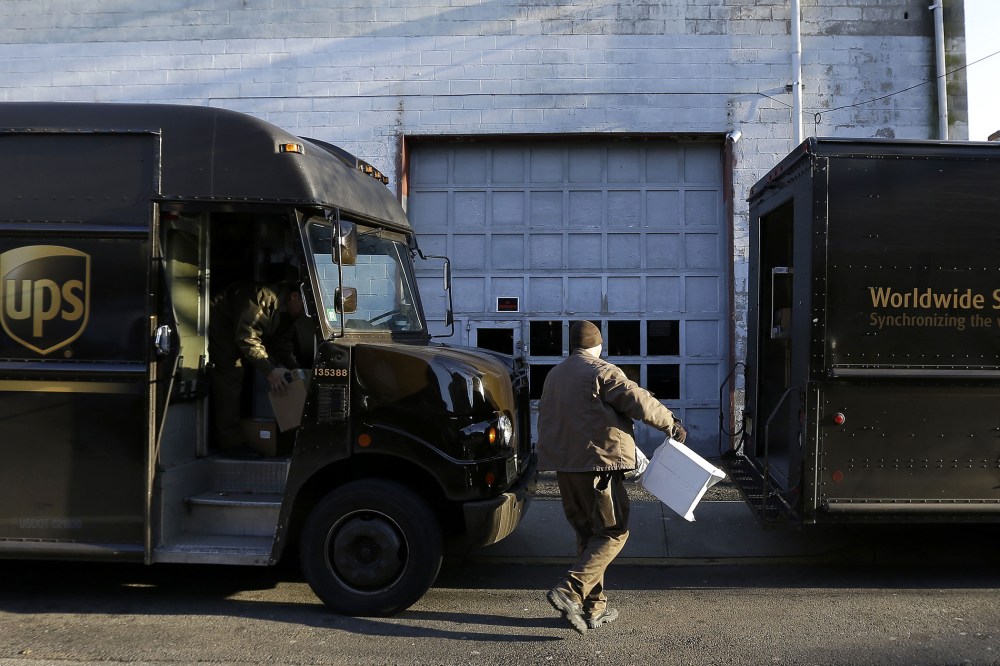 UPS delivery workers move packages from one truck to another, on Dec. 26, 2013, in Newark, N.J.