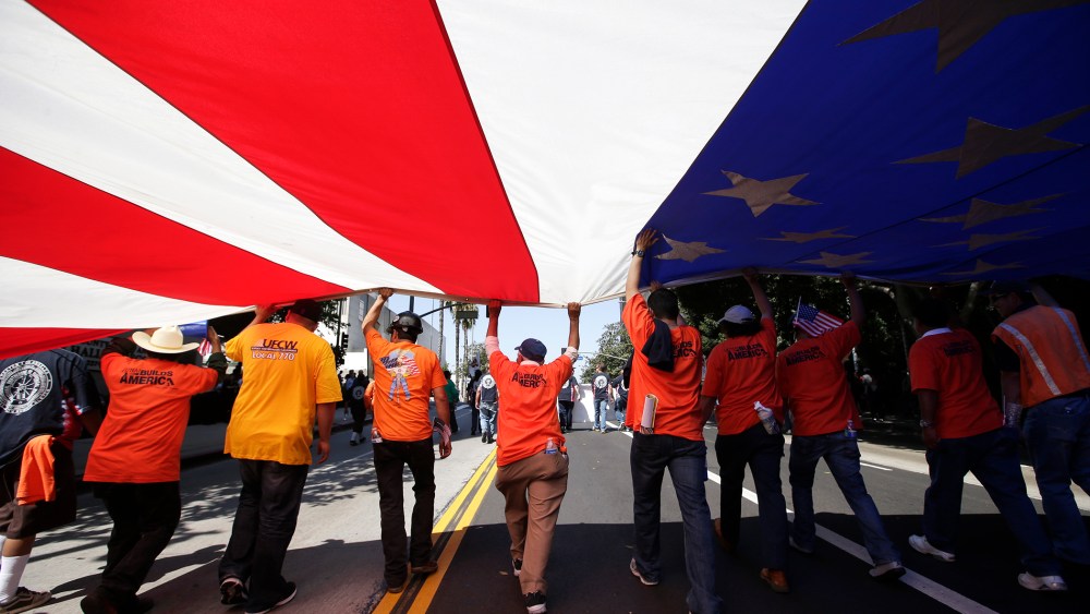 Union workers march along the street with a huge American flag during a May Day rally in Los Angeles, Calif., May 1, 2013.