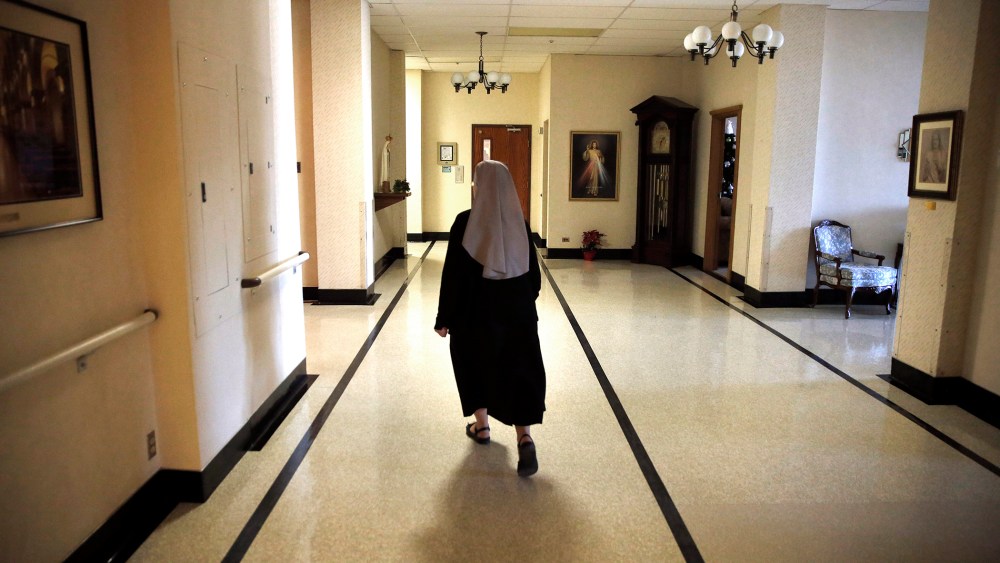 A nun walks in the hallway at the Mullen Home for the Aged, run by Little Sisters of the Poor, in Denver, Colo. (Photo by Brennan Linsley/AP)
