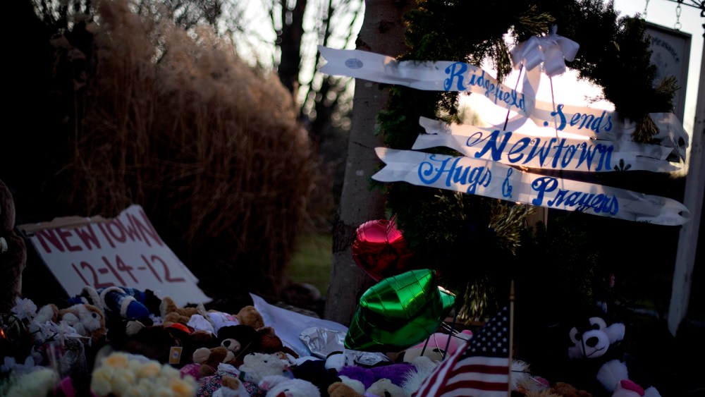 The sun sets behind a memorial for the Sandy Hook Elementary School shooting victims, Wednesday, Dec. 19, 2012, in Newtown, Conn.