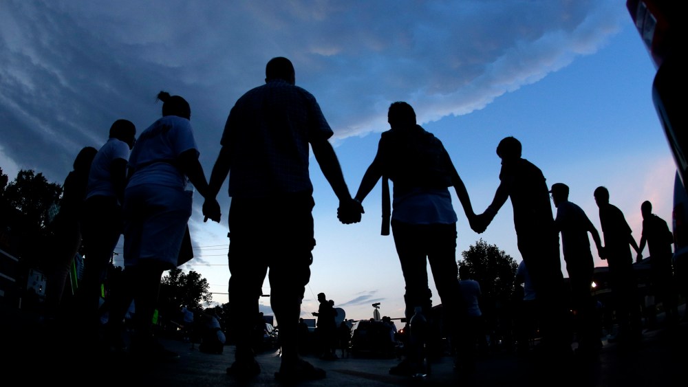 People stand in prayer after marching about a mile to the police station to protest the shooting of Michael Brown Wednesday, Aug. 20, 2014, in Ferguson, Mo.