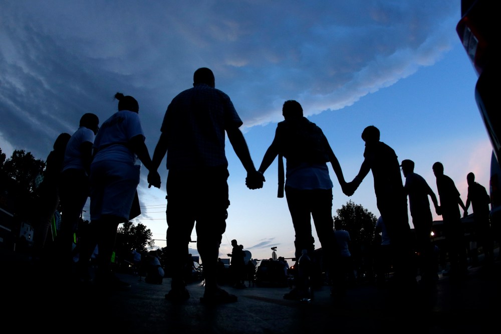People stand in prayer after marching about a mile to the police station to protest the shooting of Michael Brown Wednesday, Aug. 20, 2014, in Ferguson, Mo.