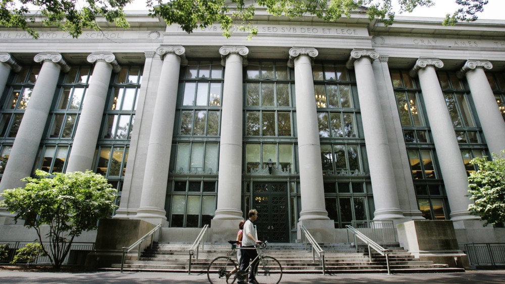 A bicyclist walks by Langdell Hall, the Harvard Law Library, on the campus of the Harvard Law School in Cambridge, Mass., Aug. 1, 2005. (Photo by Charles Krupa/AP)