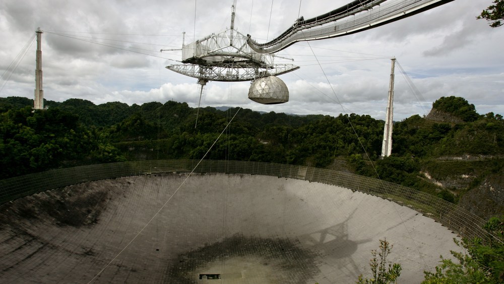 The superstructure up top and the dish below are the primary instruments of the world's largest radio telescope, currently undergoing a paintjob, near Arecibo, Puerto Rico, May 31, 2007. (Photo by Brennan Linsley/AP)