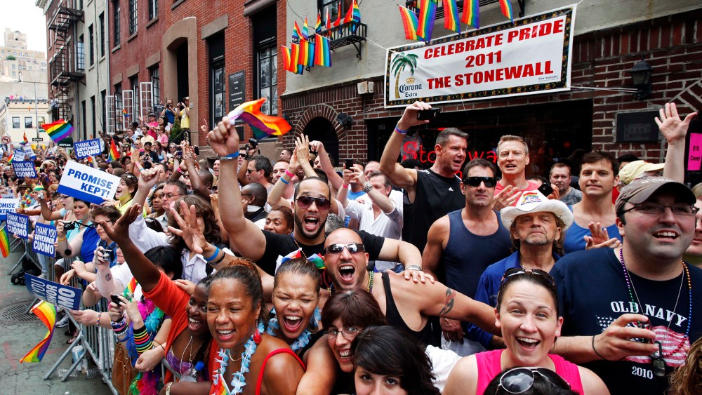 People cheer while standing in front of the Stonewall Inn on Christopher Street in Greenwich Village as the annual Gay Pride parade passes, June 26, 2011 in New York, N.Y. (Photo by Mark Lennihan/AP)