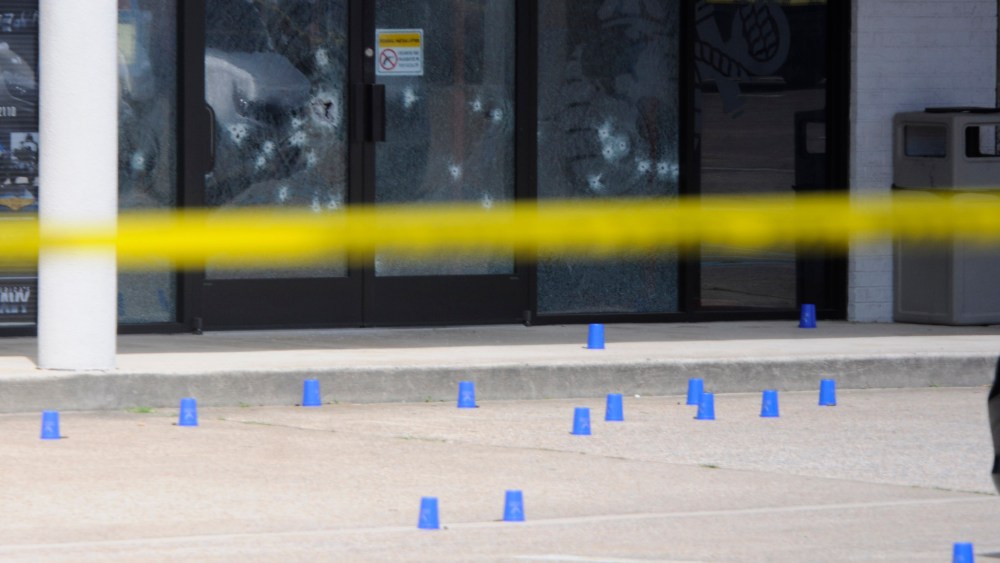 The windows of the Armed Forces Recruitment Center have several bullet holes from a shooting as the area is cordoned off with blue shell casing markers in the parking lot, July 16, 2015 in Chattanooga, Tenn. (Tim Barber/Chattanooga Times Free Press/AP)