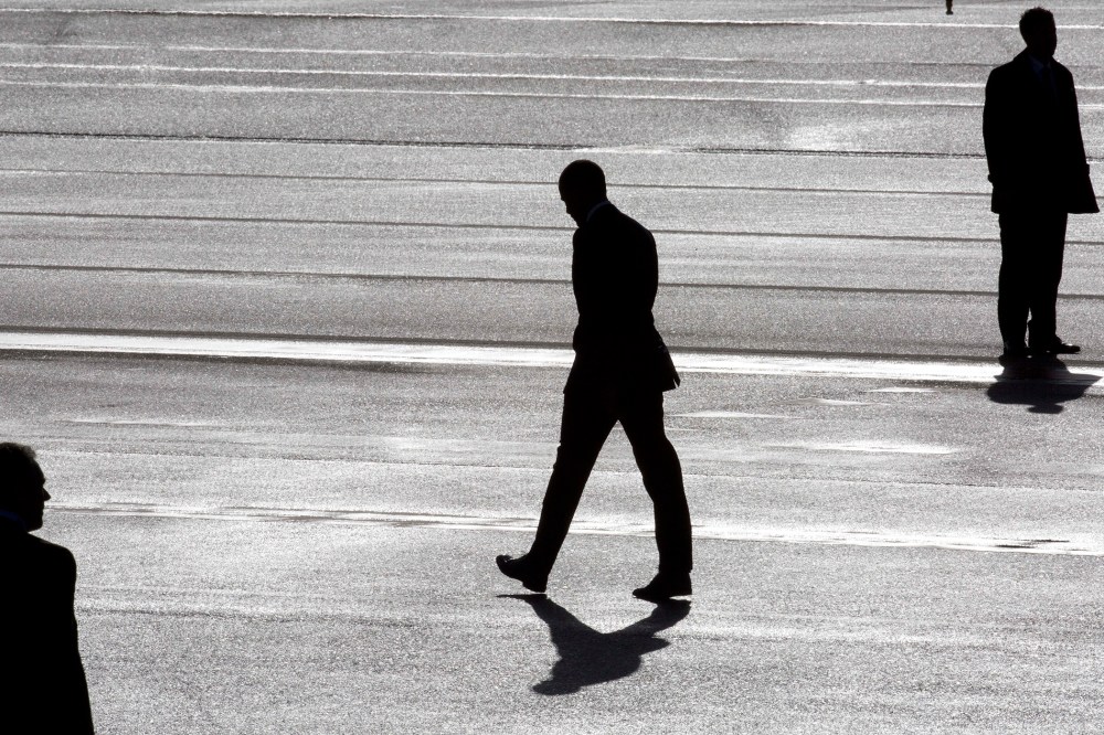 President Barack Obama, center, and two secret service agents are silhouetted as he walks towards Marine One helicopter upon arrival at Schiphol Amsterdam Airport, Netherlands March 24, 2014. (Photo by Peter Dejong/Pool/AP)