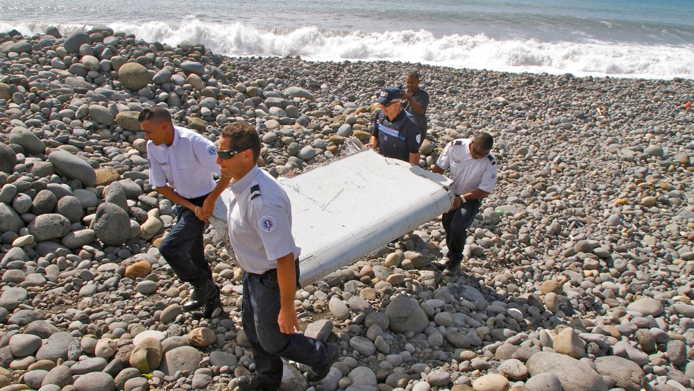 French police officers carry a piece of debris from a plane in Saint-Andre, Reunion Island (Photo by Lucas Marie/AP).