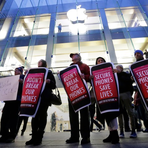 Protesters carry placards outside an Apple store in Boston, Feb. 23, 2016. (Photo by Steven Senne/AP)