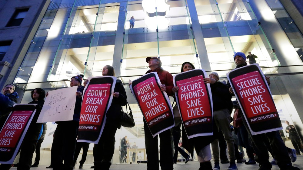 Protesters carry placards outside an Apple store in Boston, Feb. 23, 2016. (Photo by Steven Senne/AP)
